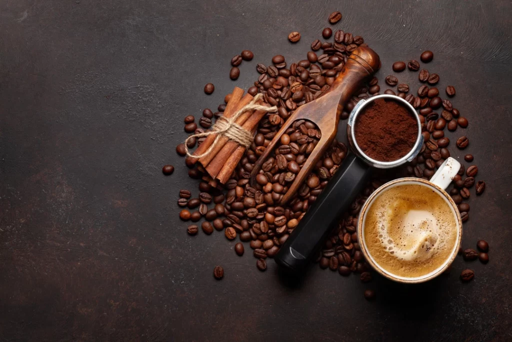 Roasted coffee beans, ground powder of beans, and hot coffee in the cup.