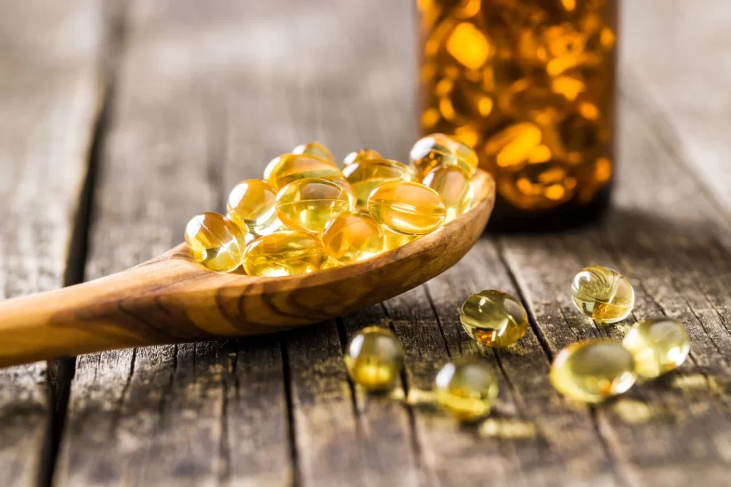 omega 3 capsules on a wooden spoon and bottle.