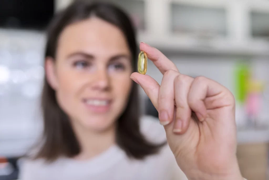 young beautiful woman holding an omega 3 capsule before intaking.